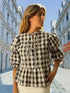 Woman wearing checkered puff sleeve blouse with tie detail