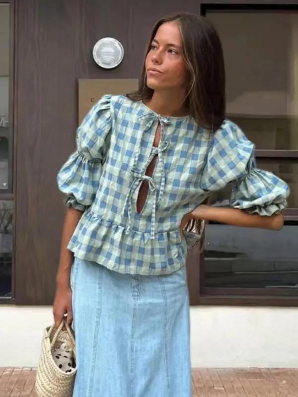 Blue checkered puff sleeve blouse with tie detail, standing woman