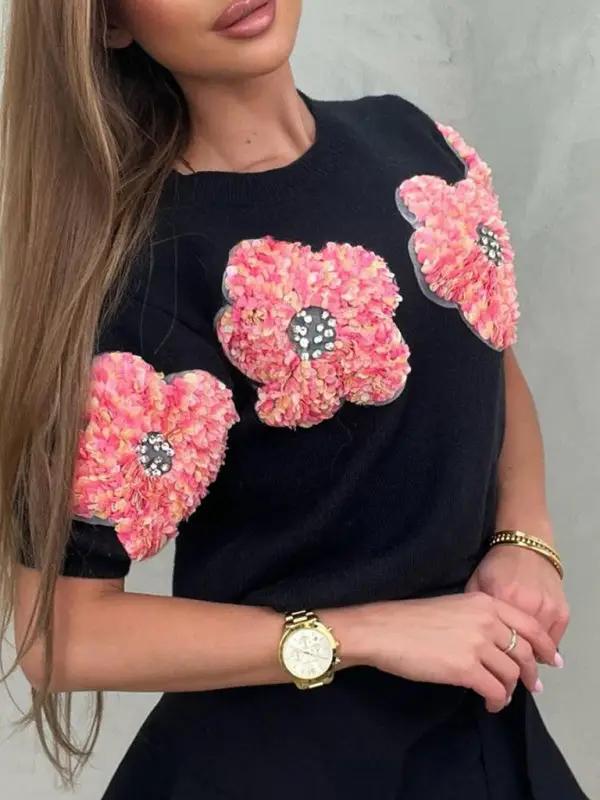Close-up of black sweater with pink flower accents.