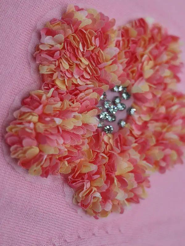 Close-up of pink flower detail on sweater.