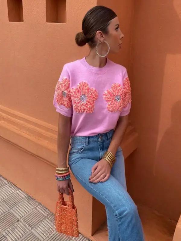 Model in pink sweater with floral design, seated pose.