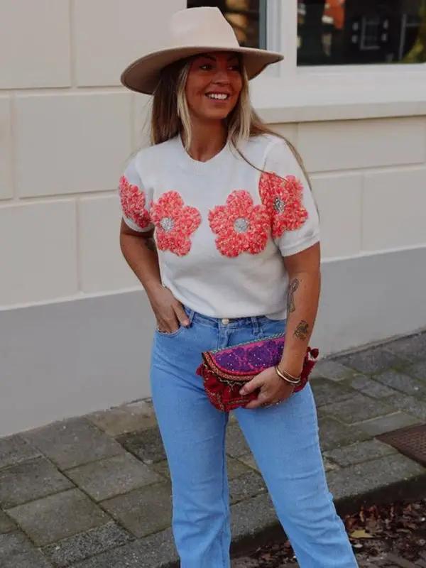 Model in white sweater with pink flower design.