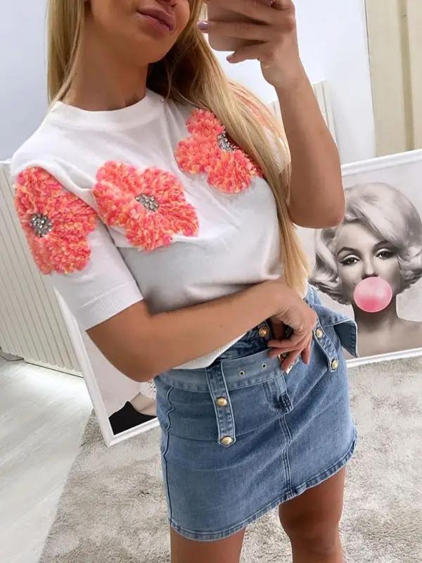 White sweater with floral design, paired with denim skirt.