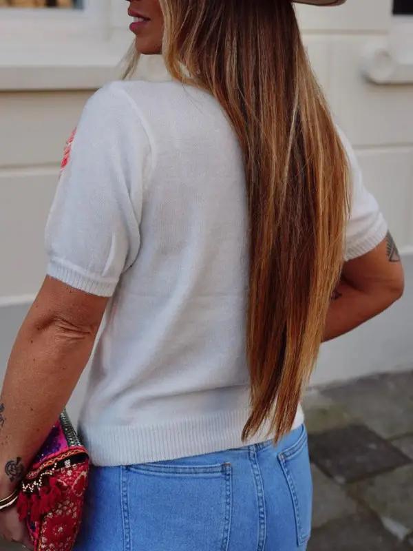 Back view of white sweater with floral accents.