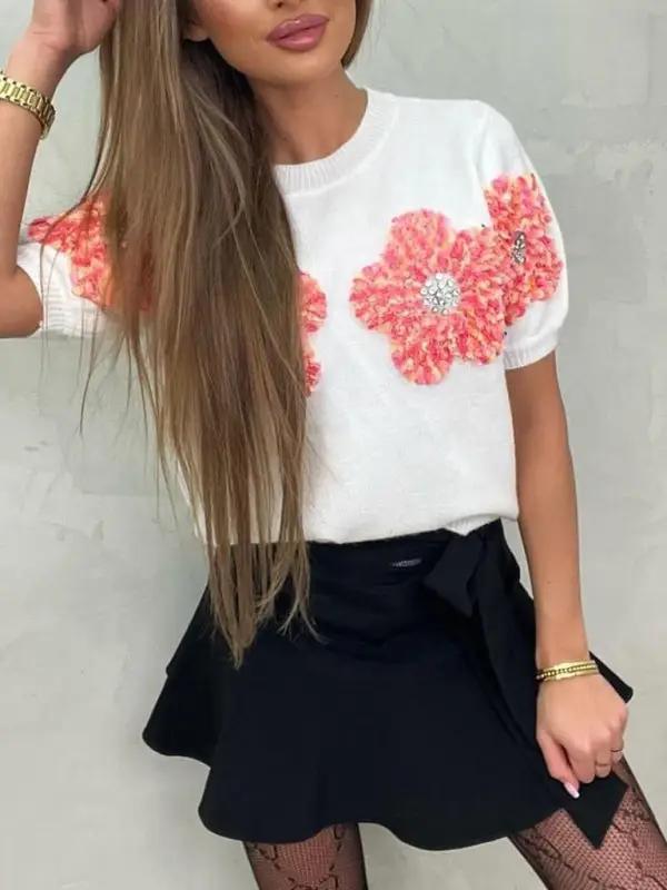 White sweater with pink flowers, styled with black skirt.