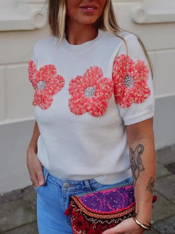 White sweater with pink floral design, round neck.