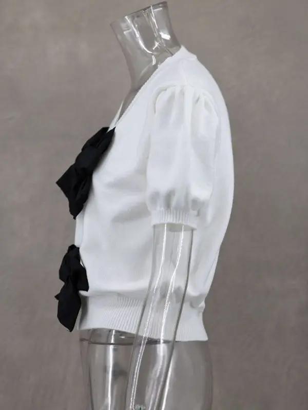 Side profile of white sweater with black bows on mannequin
