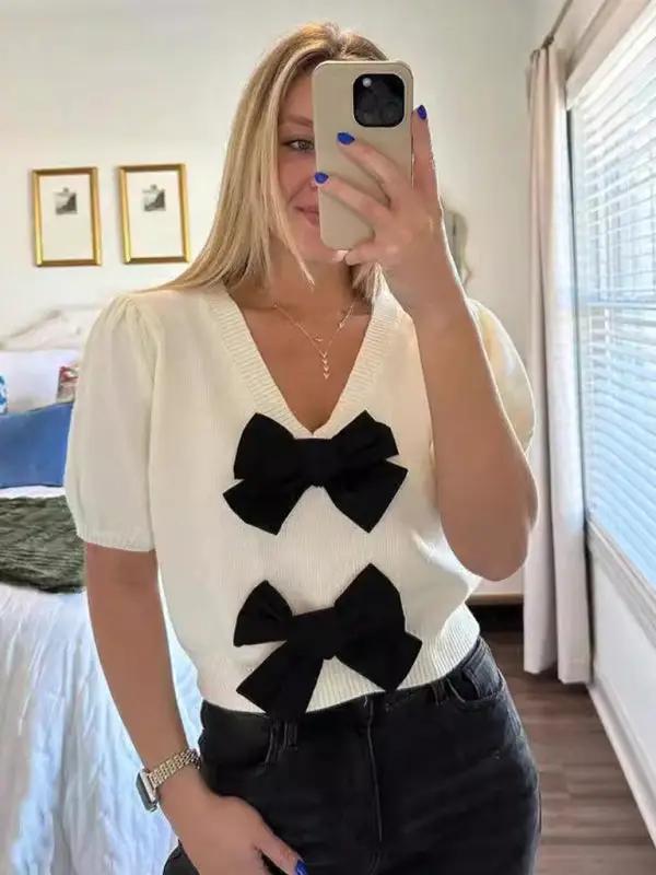 White V-neck sweater with black double bows, worn by model