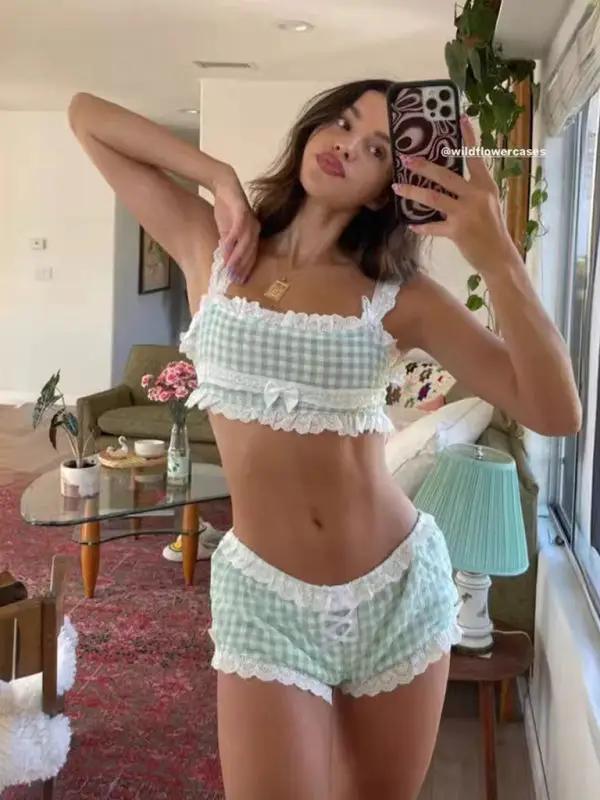 Woman in plaid pajamas taking a mirror selfie indoors