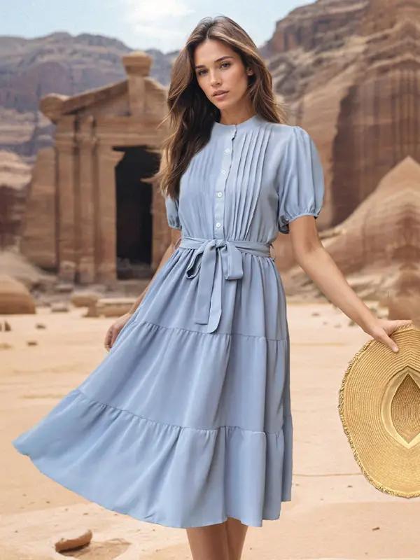 Woman in blue stand collar midi dress holding a hat