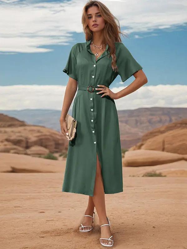 Woman in green lapel single breasted dress holding clutch.