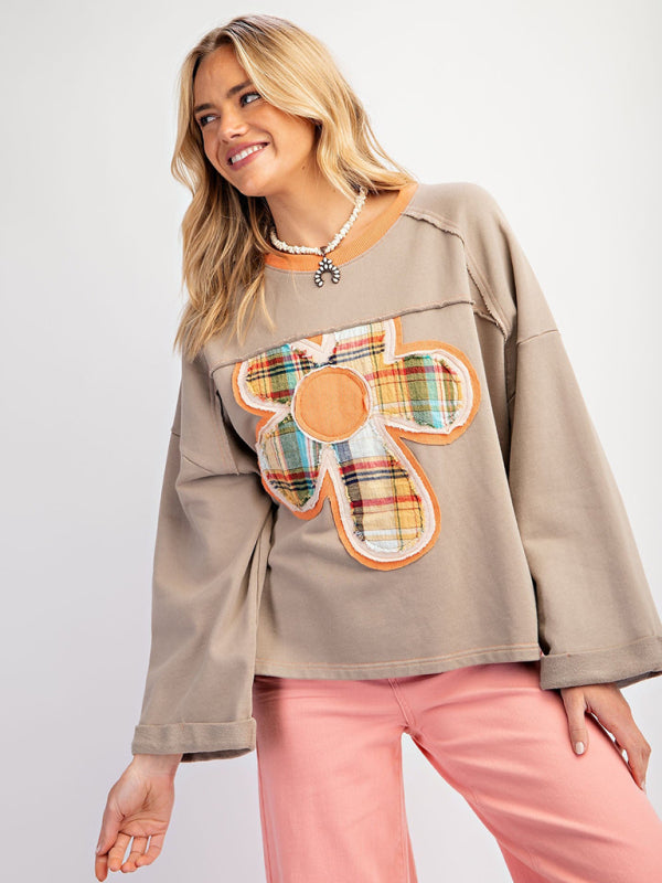 Gray floral patch top with pink pants, smiling