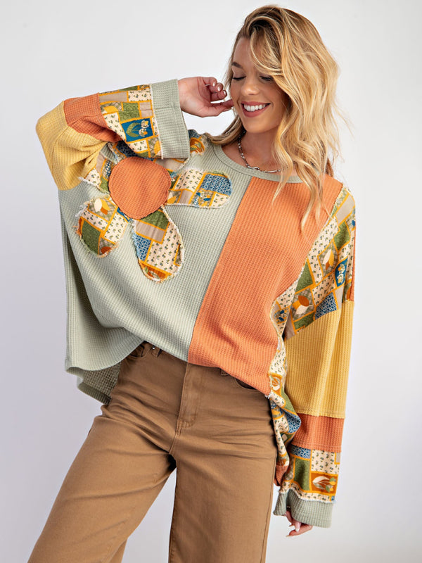 Model in green and orange contrast print waffle top smiling.
