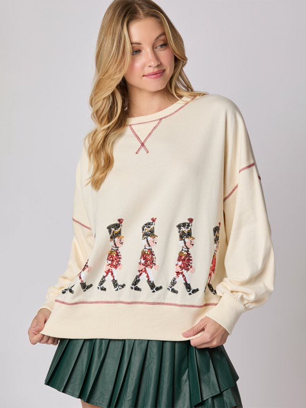 Model in cream sequin soldier sweatshirt with green skirt