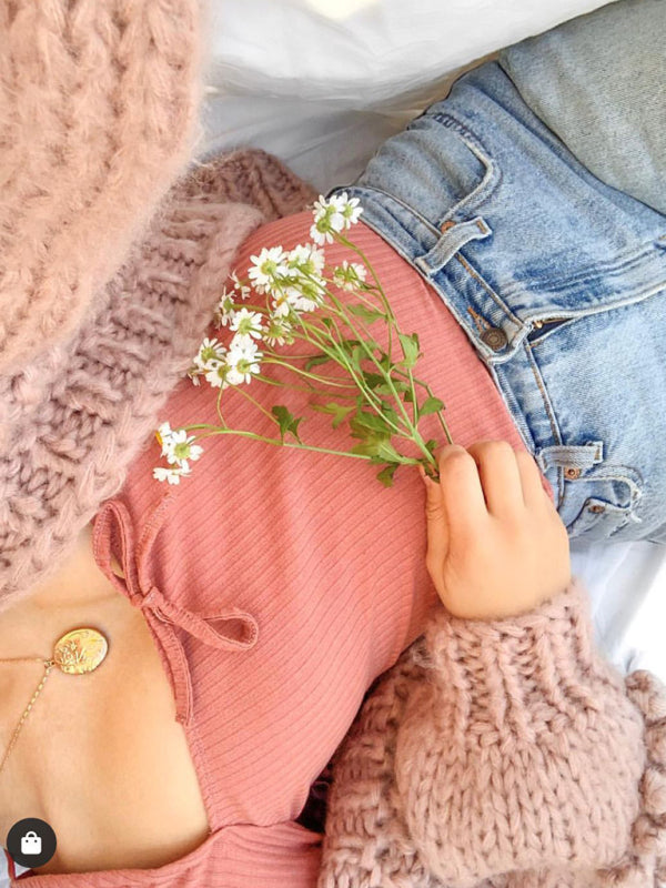 a little girl laying on a bed with a flower in her hand