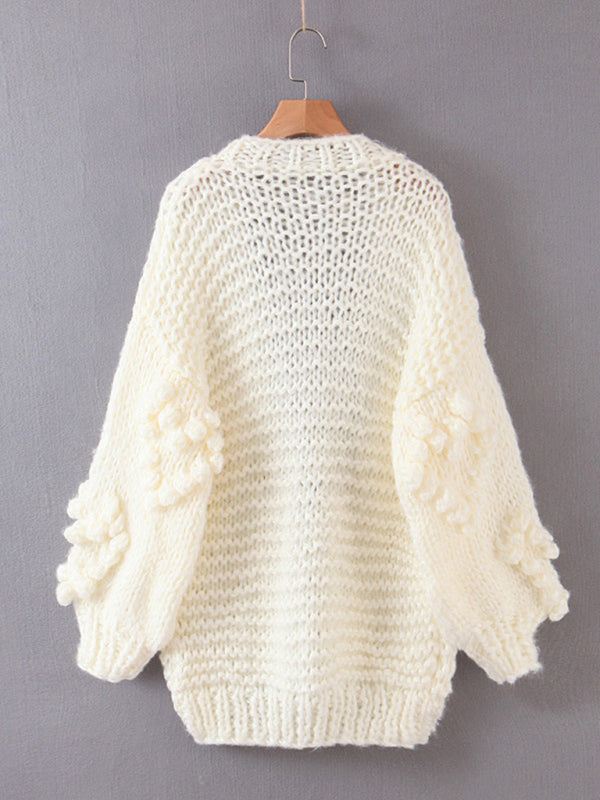 a white sweater hanging on a wooden hanger