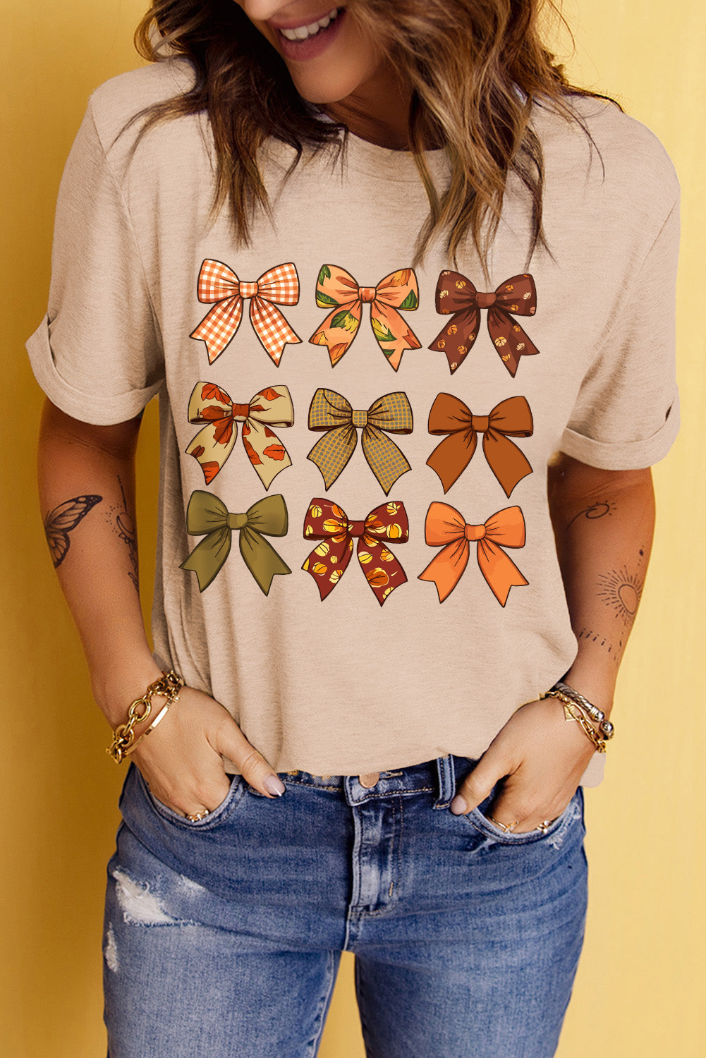 Beige T-shirt with colorful bow graphic design, round neck.