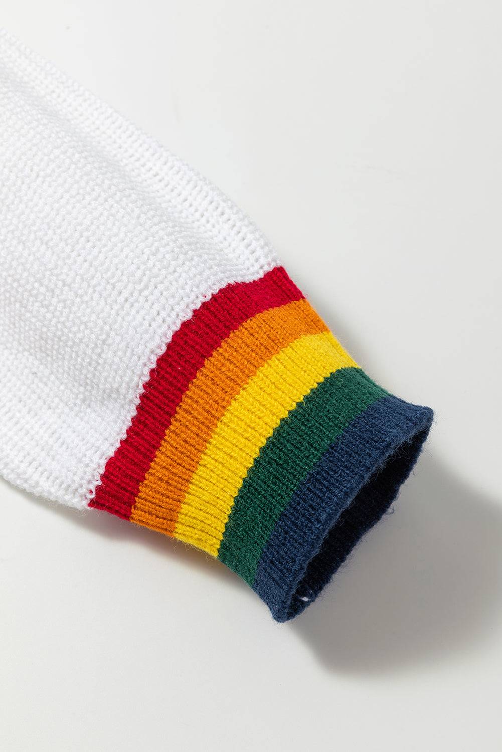 Close-up of white sweater sleeve with rainbow trim