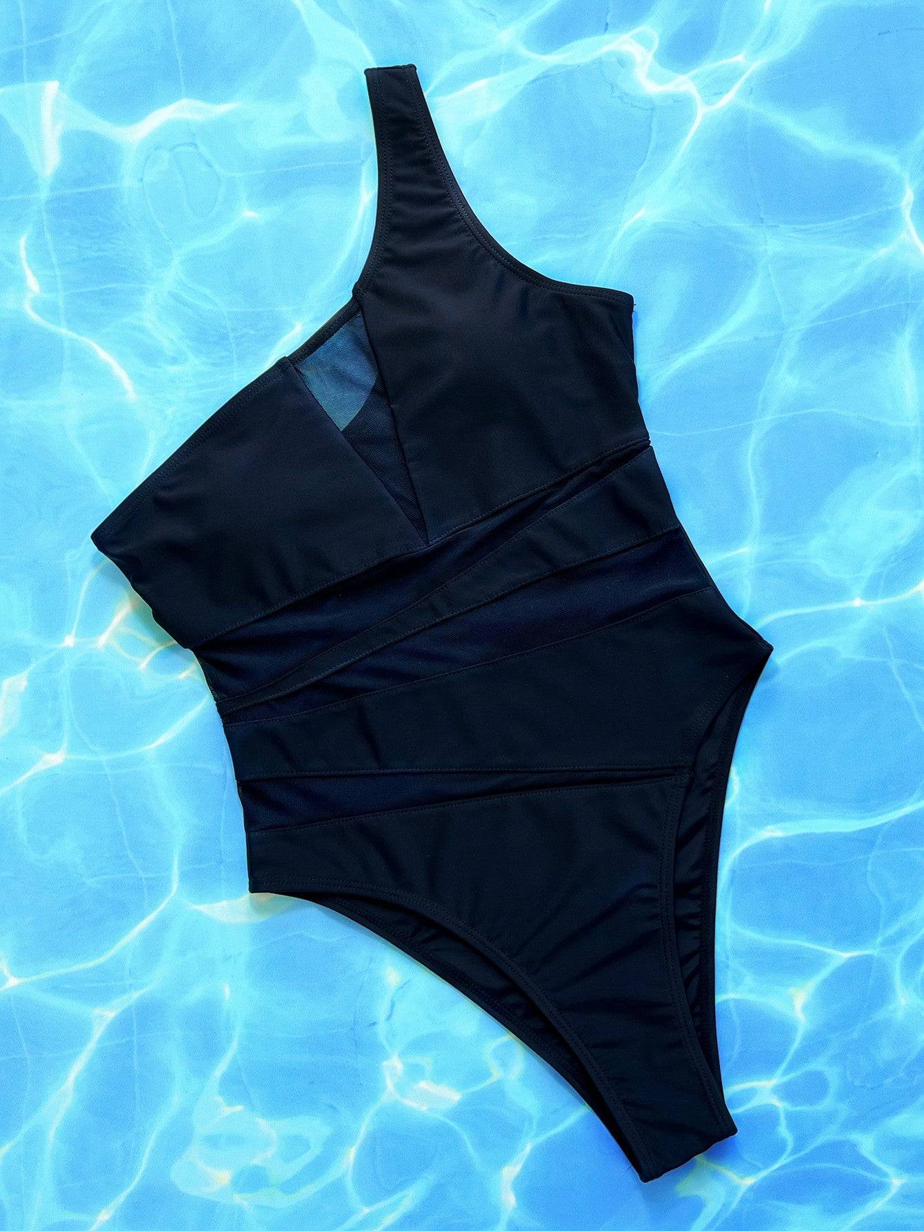 One-shoulder black swimsuit with mesh on water backdrop.