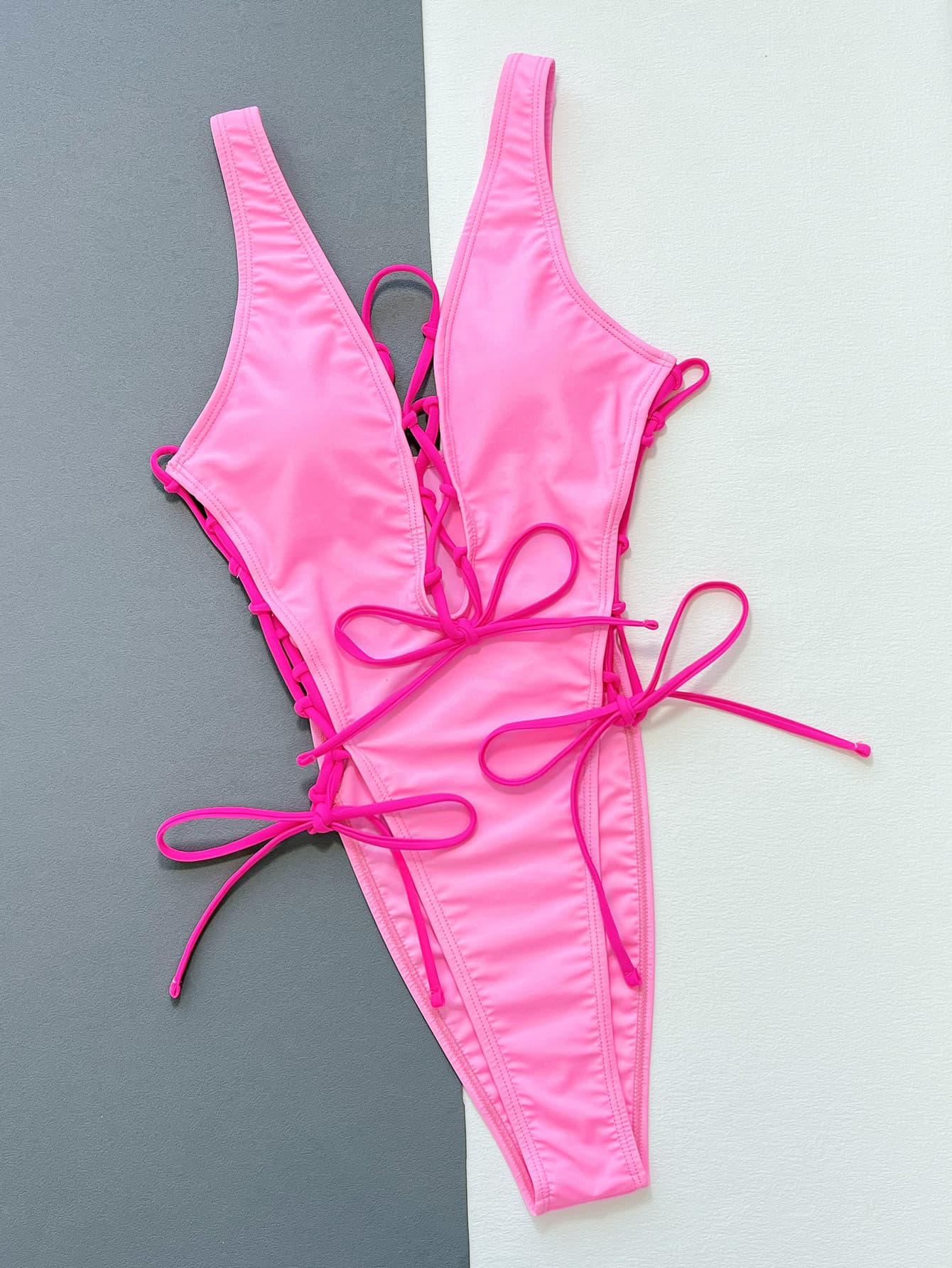 Pink one-piece swimsuit with lace-up design and bows