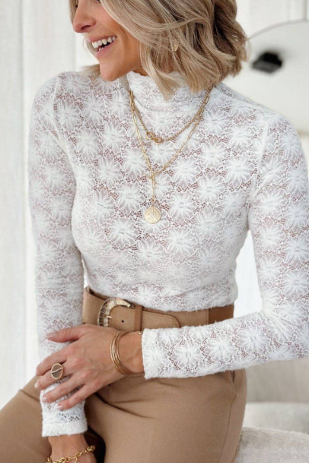 Elegant white lace top with mock neck and long sleeves.