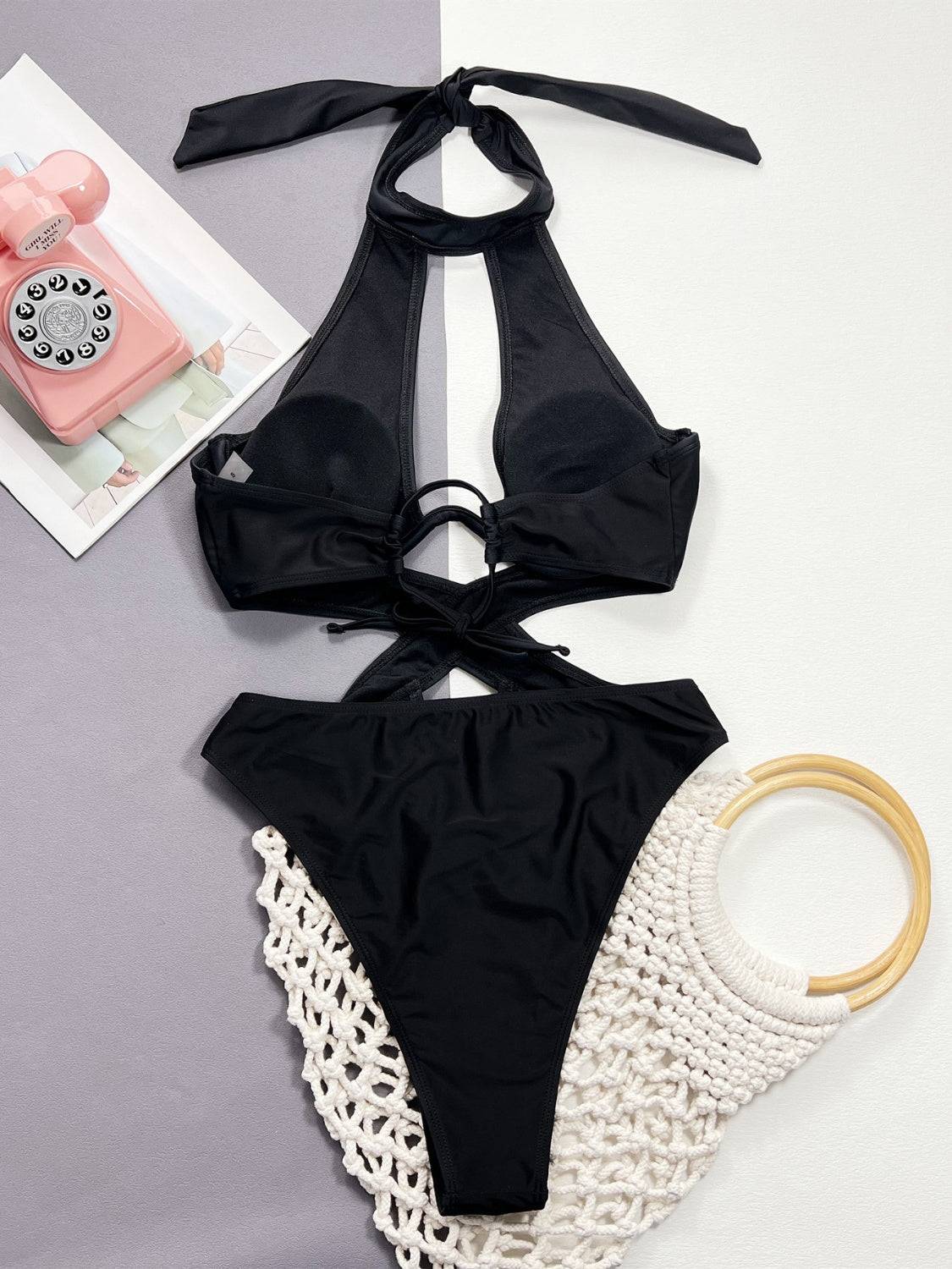 Back view of black cutout halter neck one-piece swimwear flat lay