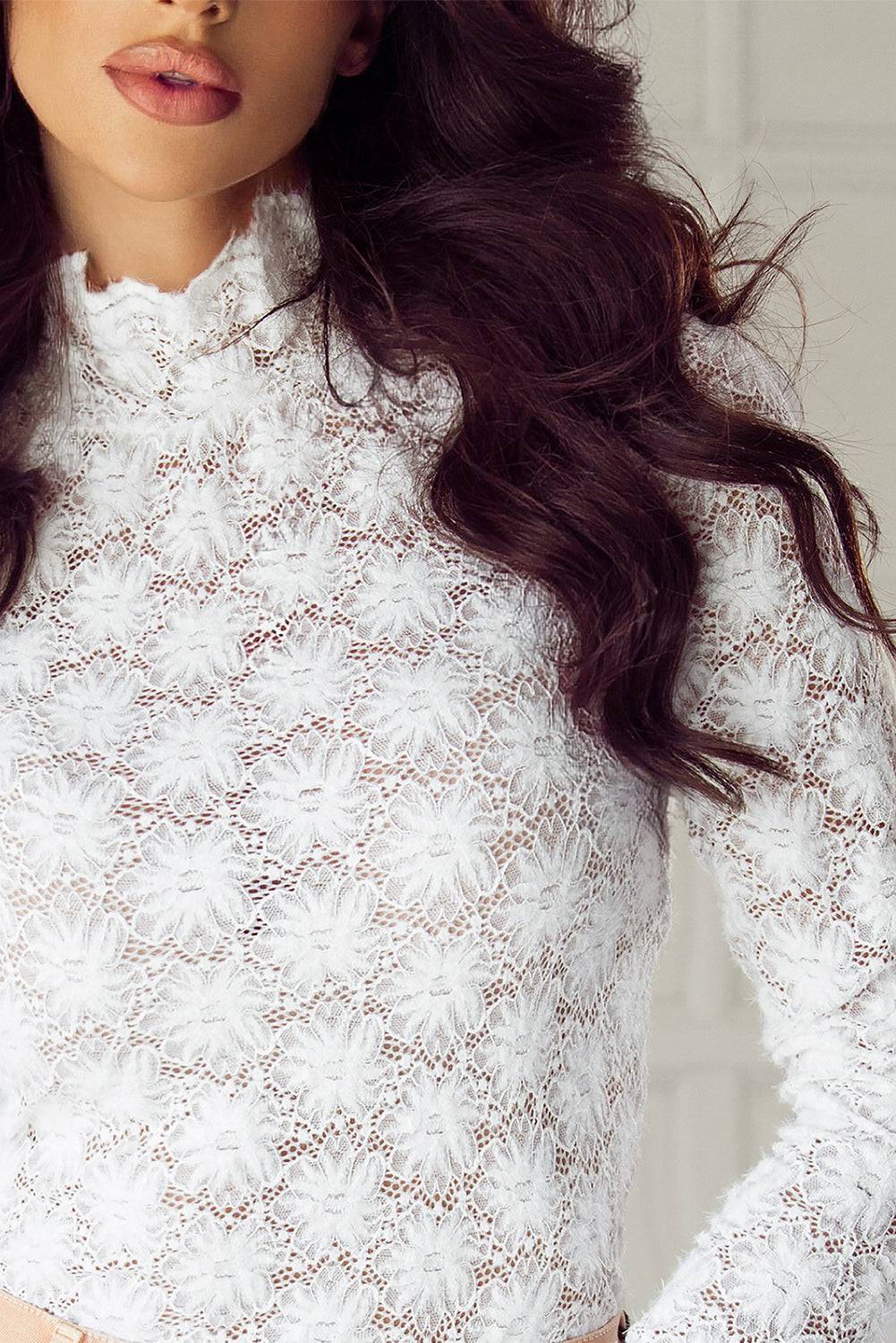 Detailed view of floral lace pattern on white top.