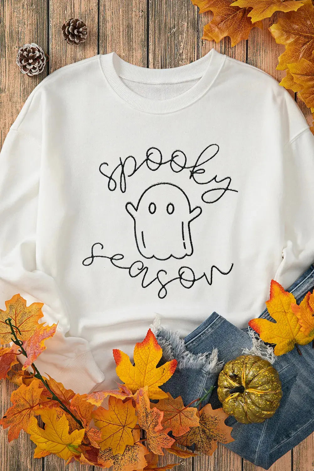 Ghost graphic sweatshirt styled with autumn leaves.