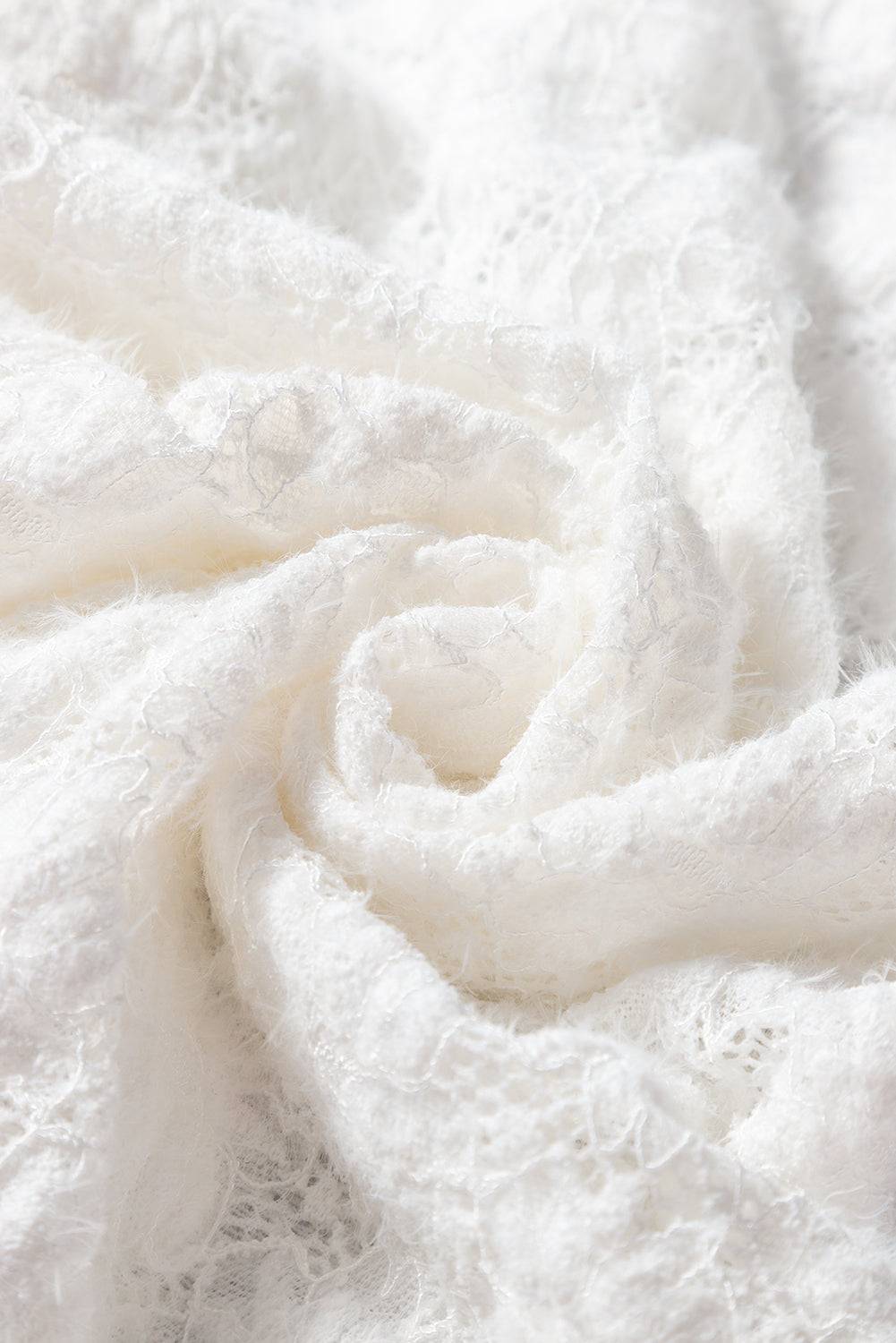 Detailed texture of white lace fabric in floral pattern.