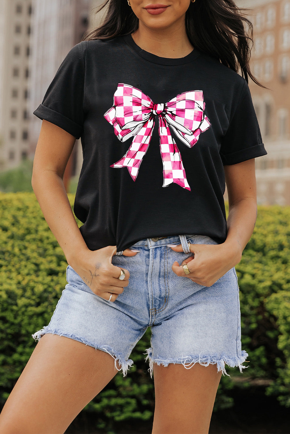 Black T-shirt with pink bow graphic, round neck, short sleeves.