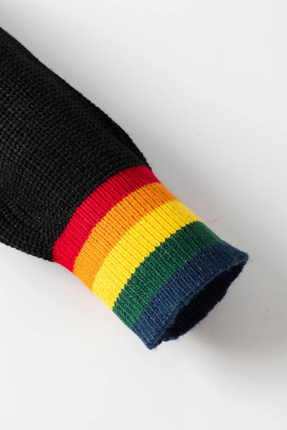 Close-up of black sweater sleeve with rainbow trim