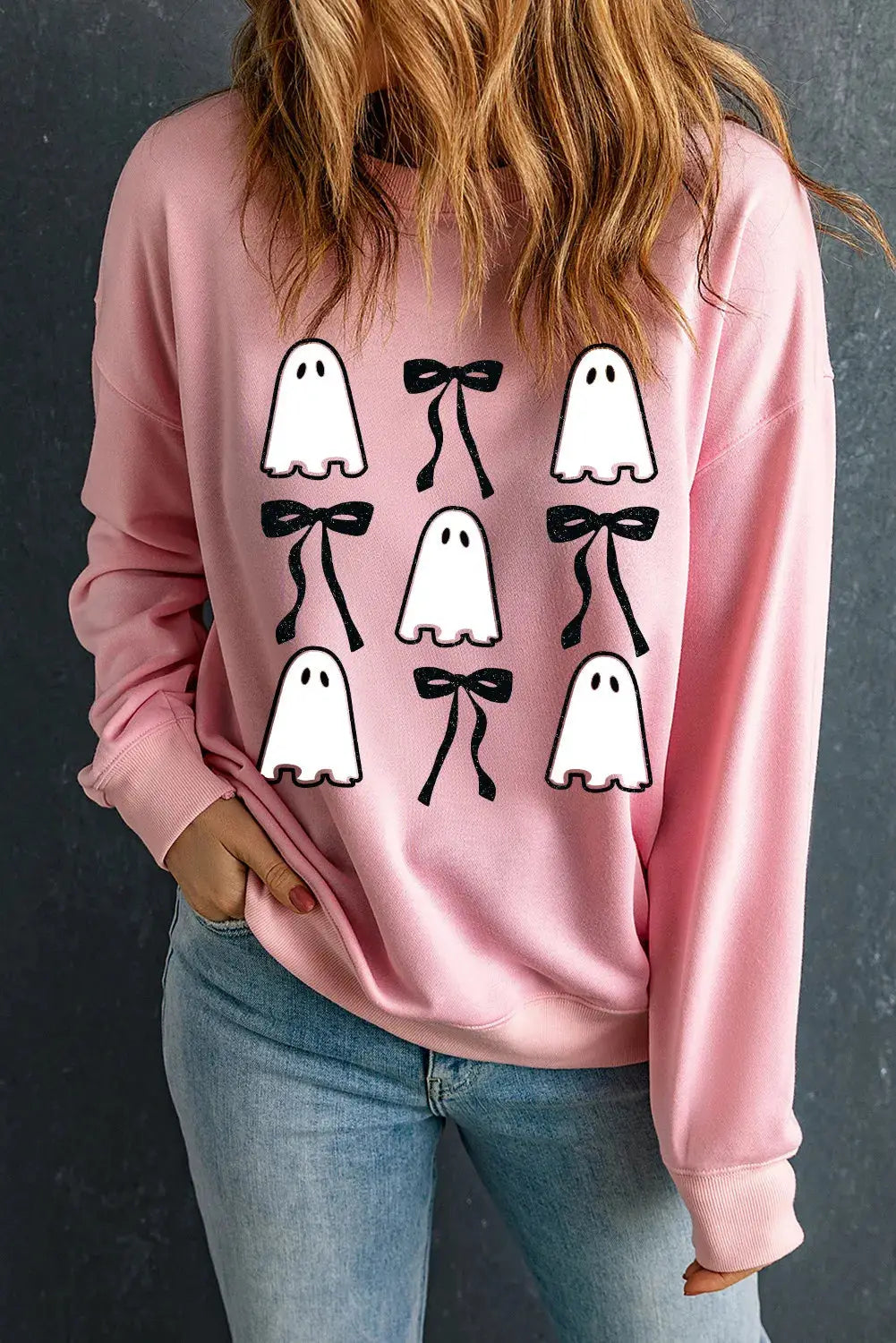 Pink sweatshirt with ghost and bow design, round neck, long sleeves.