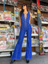 Woman in open back high waist denim jumpsuit at magazine stand