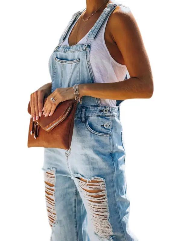 Side view of washed ripped blue overalls jeans with clutch