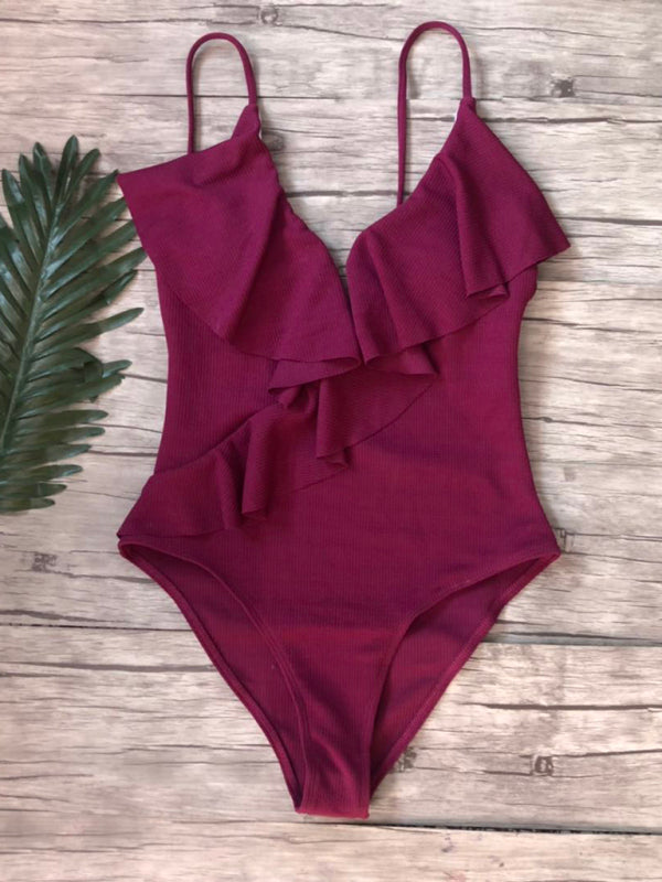 Red ruffled one-piece swimsuit on wooden background