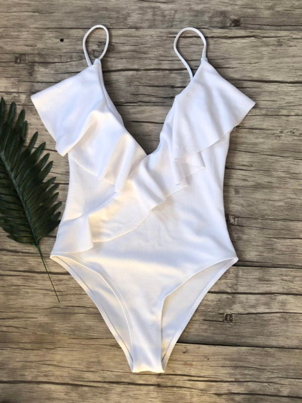 White ruffled one-piece swimsuit on wooden background