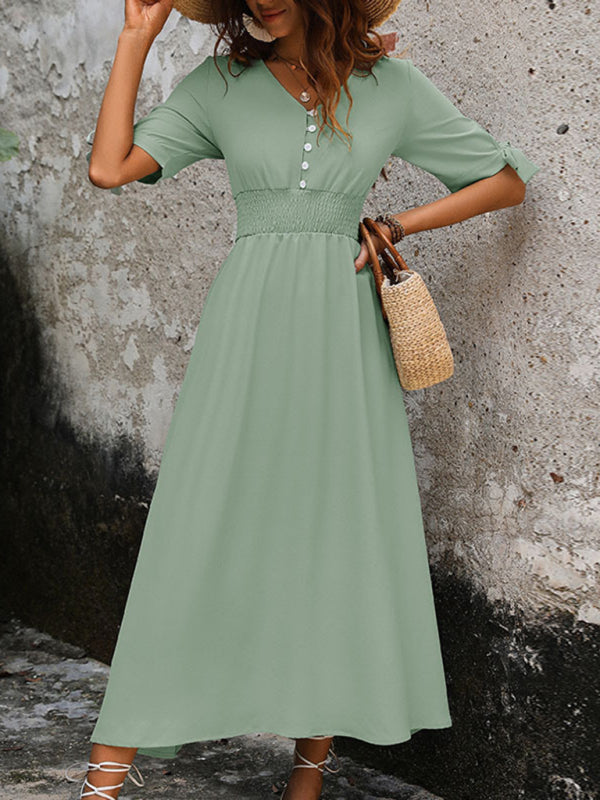 Elegant V-neck belted midi dress in green, worn with a hat.