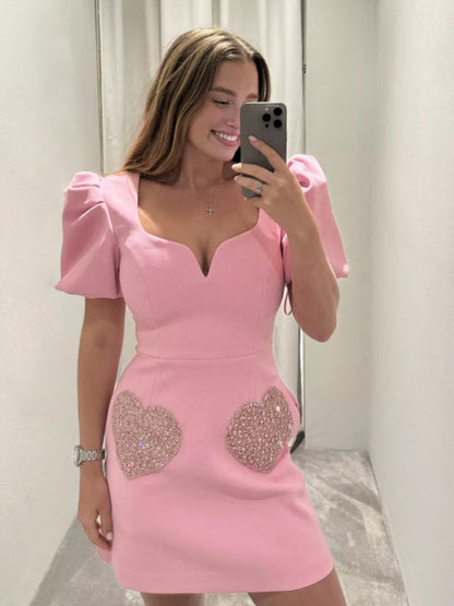 Woman in pink V-neck dress with sequin heart accents