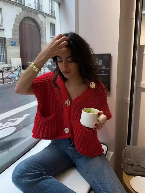 Woman sitting indoors wearing red knitted vest cardigan