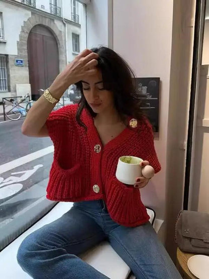 Woman sitting indoors wearing red knitted vest cardigan