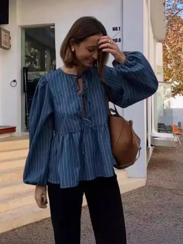 Woman wearing a blue striped lace-up loose top outdoors
