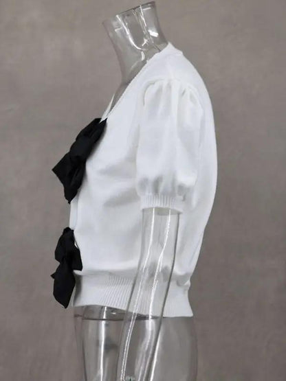 Side profile of white sweater with black bows on mannequin