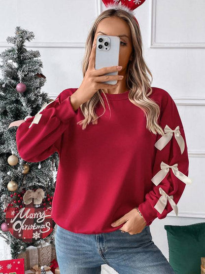 Close-up of red Christmas sweater with bows, holding phone