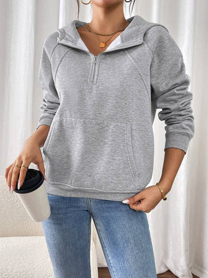 Gray hoodie paired with jeans, holding a coffee cup.