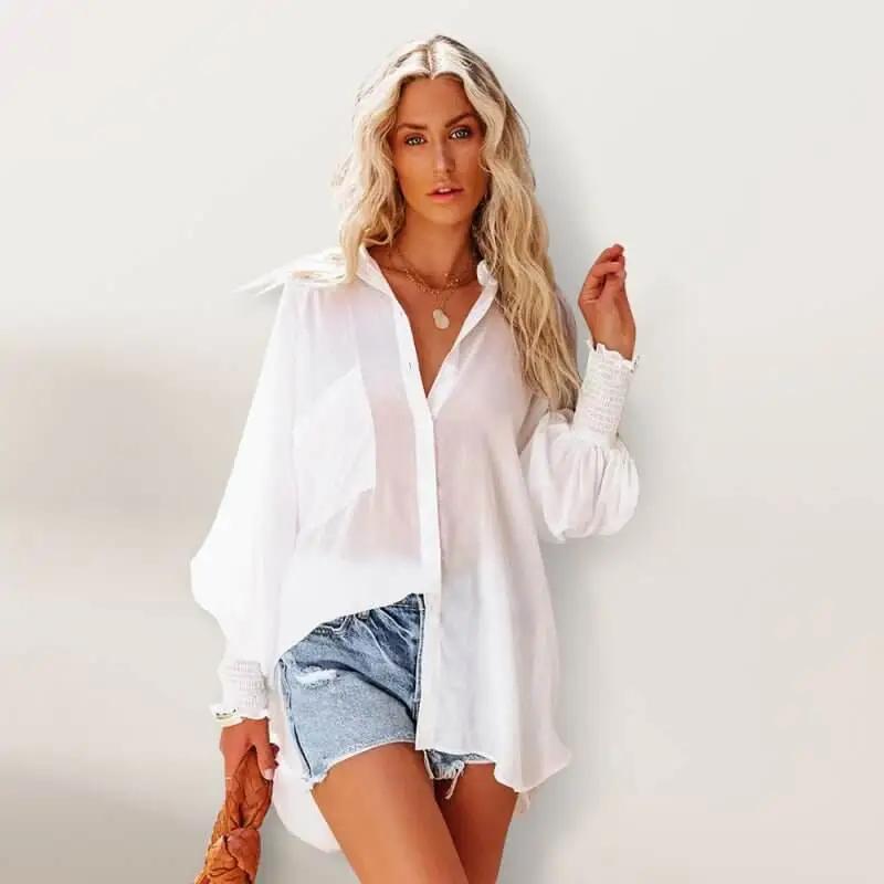 a woman posing in a white shirt and denim shorts