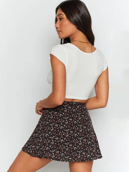 a woman in a white top and black floral print skirt