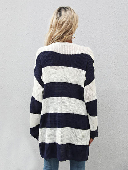 a woman standing in front of a wall wearing a blue and white striped sweater