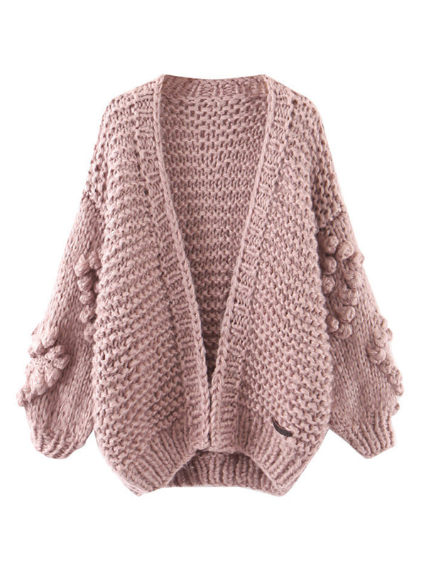 a pink sweater with pom poms on the sleeves