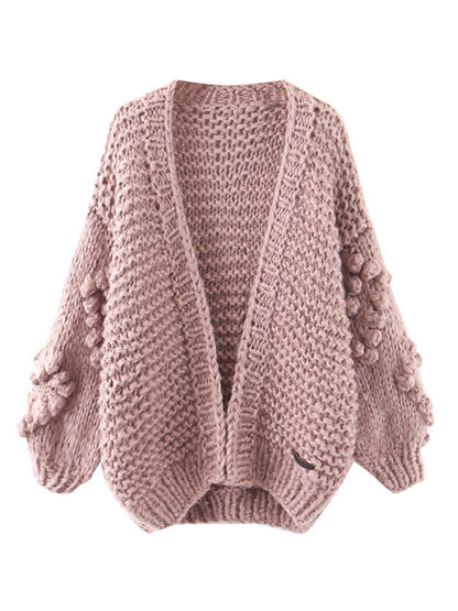 a pink sweater with pom poms on the sleeves