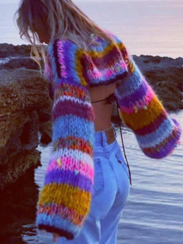 a woman standing in the water wearing a colorful sweater
